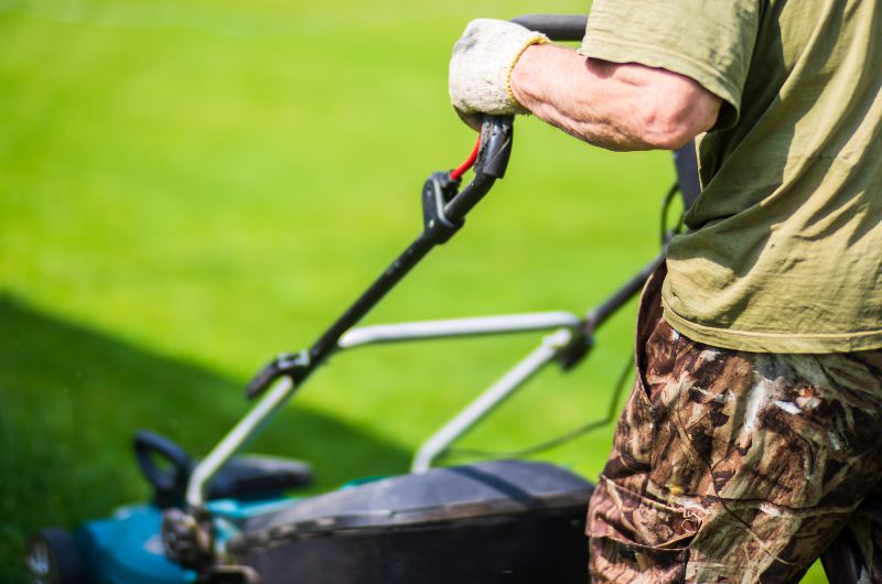 over shoulder view of man mowing lawn